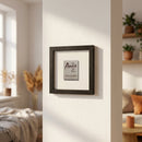 Decorative Anis Cafe Framed Print with black matte finish, mounted on wall in cozy living room setting with natural light.