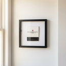 Full-body view of 'Chicago Athletics Association' framed print hanging on white wall, showcasing elegant wooden frame and detailed high-quality paper in cozy interior setting.