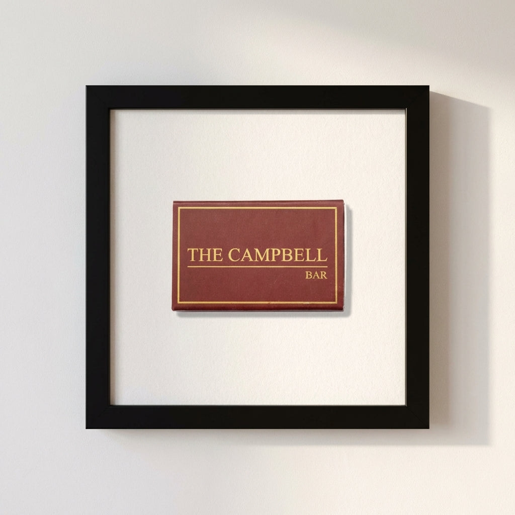 Product shot of Campbell Bar Matchbox framed print on a white wall, illuminated by soft natural warm light in a cozy environment.