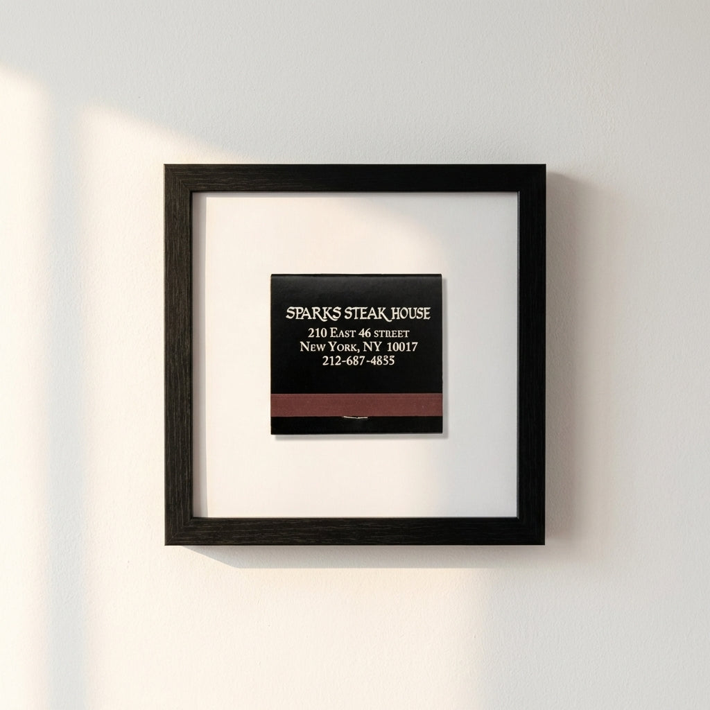 High-quality framed Sparks Steak House Matchbox print on white wall, captured in a warm, inviting natural light setting.
