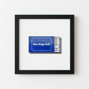 Framed Blue Ridge Grill artwork hanging on a neutral wall in a warm, inviting living room with natural light.
