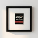 Framed 'The Royal American' poster on a white wall in a cozy living room with warm lighting and natural ambiance.