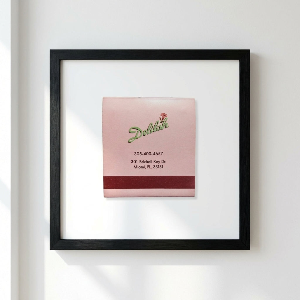 Full-body view of the 'Delilah' framed poster on white wall, emphasizing craftsmanship, natural wood frame, and elegant room setting.