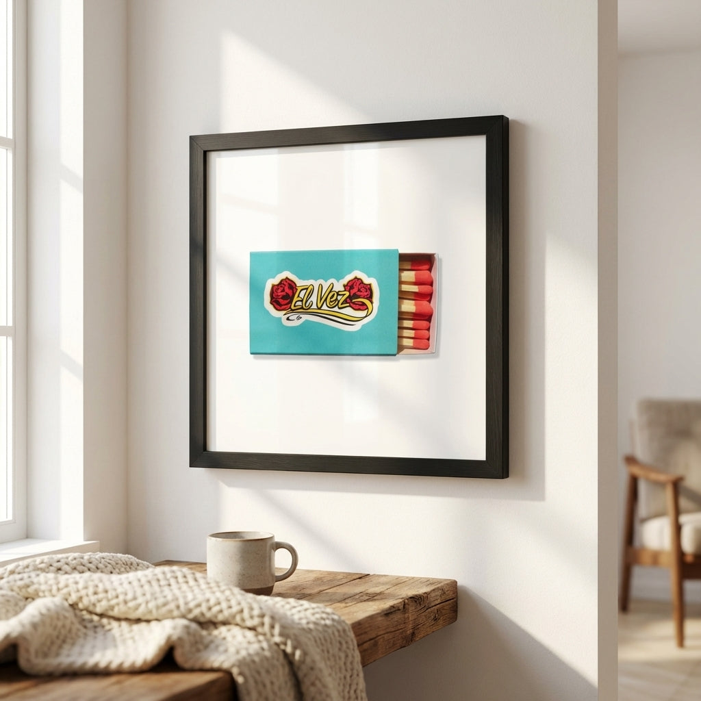 Close-up of the El Vez poster in a wooden frame on a white wall, showing micro-texture details, natural shadows, and warm daylight in a minimal setting.