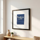 Framed 'Emmett’s on Grove' poster hanging on a plain white wall in a cozy interior, highlighting glossy and matte textures with warm natural lighting.