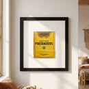 Close-up of Firecrackers framed print on white wall with warm lighting, highlighting glossy and matte textures and protective acrylic front.