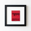 High-resolution photo of Frontier Lounge Framed Print hanging on a white wall in a cozy living room with warm natural light, emphasizing the matte black wood frame.