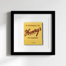 Close-up of Henry's Framed Print on white wall, highlighting partly glossy matte finish, high-quality paper, black wood frame, natural warm lighting.