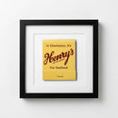 Full view of Henry's Framed Print hanging on white wall in cozy setting, emphasizing 12x12 size, textured paper, elegant wood frame, warm natural lighting.