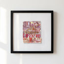 12x12 inch framed black and white poster of The Hotel Chelsea NYC hanging on a white wall in a home with warm lighting.