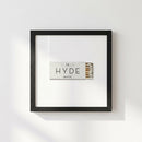 Elegant Hyde framed poster on a plain white wall with natural lighting, showcasing textured high-quality paper and a wood frame.