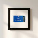 High-resolution shot of Little Prince framed print on white wall, centered, warm soft lighting, detailed textures.