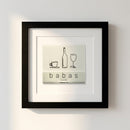 Close-up of 'Babas on Cannon' framed print on white wall in a warm, inviting living room with natural window light.