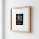 Lifestyle shot of 'Lottie's Chicago' framed poster in a warm living space with natural lighting, highlighting the high-quality paper, glass protector, and elegant wooden frame.