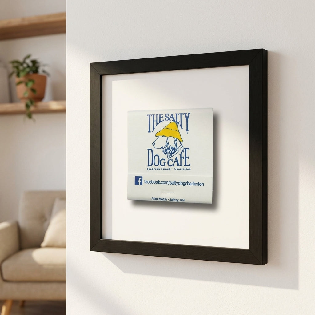 Close-up of The Salty Dog Cafe framed print on a white wall in a modern, cozy setting with warm lighting and a soft background, emphasizing texture and design.
