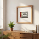 Portrait-oriented 12x12 inch Oak Steakhouse framed print on a white wall in a cozy, naturally lit living room, emphasizing warm tones and high-quality framing.