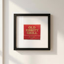 Framed 'Old Ebbitt Grill' poster on white wall in cozy living room with natural warm lighting.