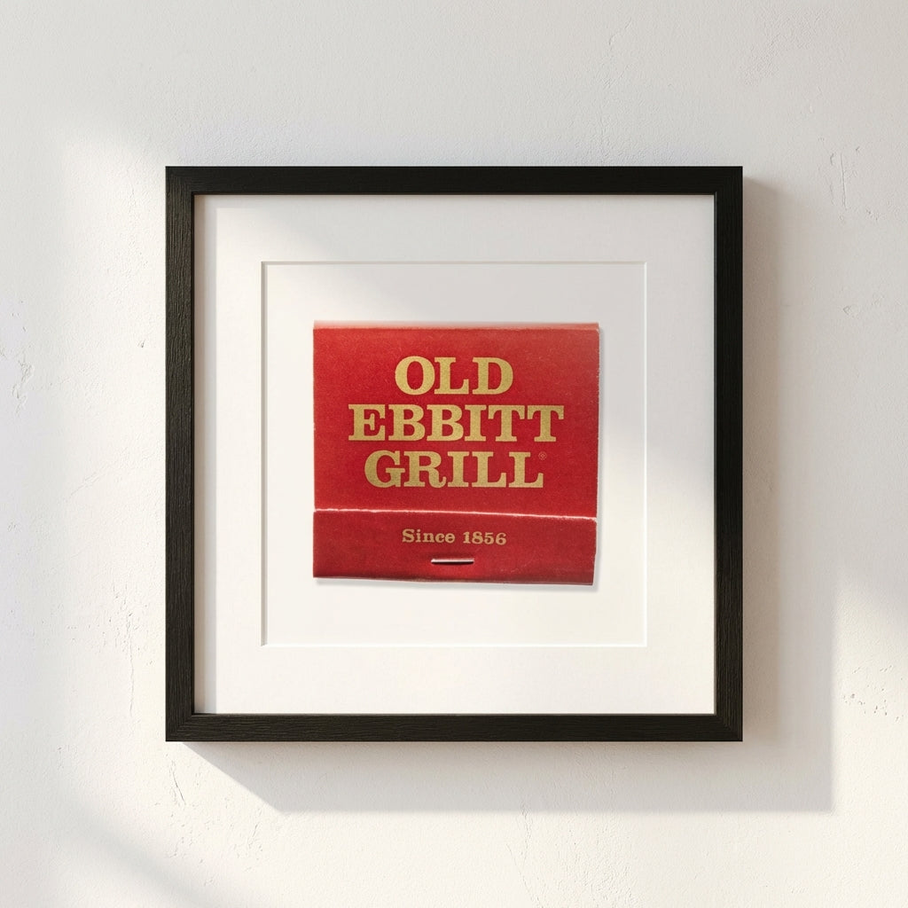 High-quality framed 'Old Ebbitt Grill' poster hanging on white wall with warm natural light, showcased in cozy room setting.
