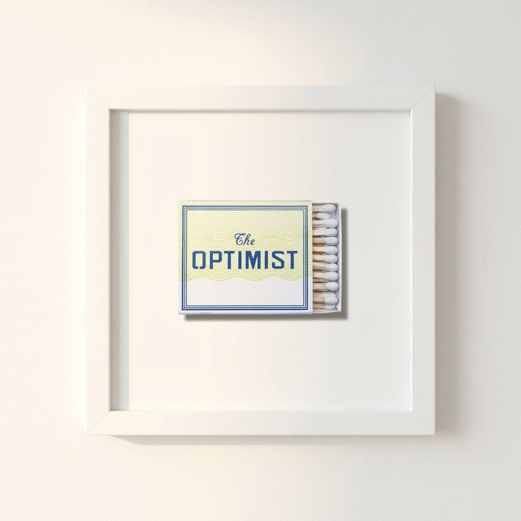 Close-up of The Optimist framed print in a minimalist home office with white wall, soft morning light, and crisp textured detail.