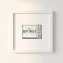 Close-up of The Optimist framed print in a minimalist home office with white wall, soft morning light, and crisp textured detail.