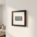 Small framed print titled Tiny Lou’s on white wall, wooden matte black frame, cozy natural window light, macro detailed photo.